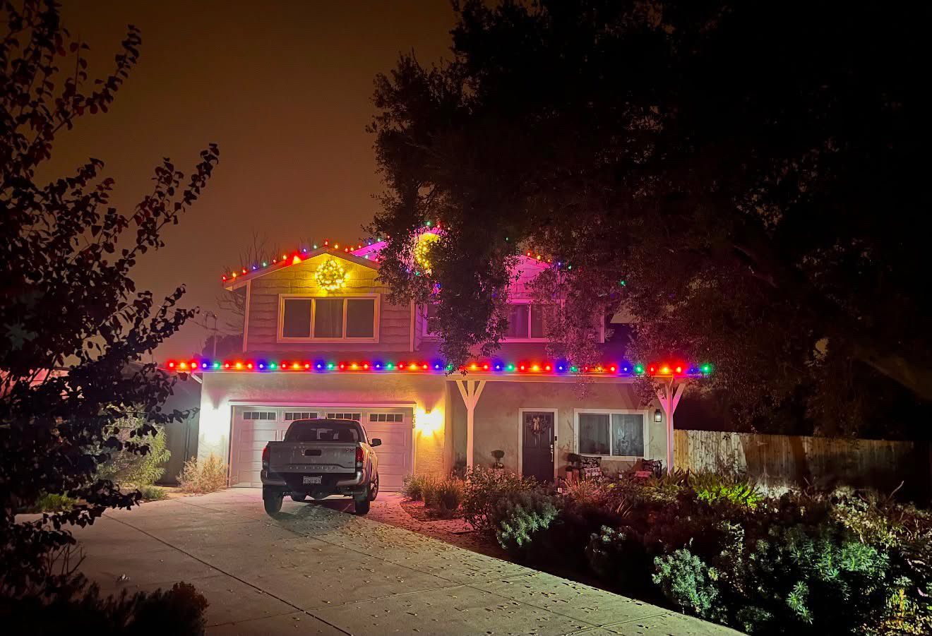 Two-story home with multicolor Christmas roofline lights