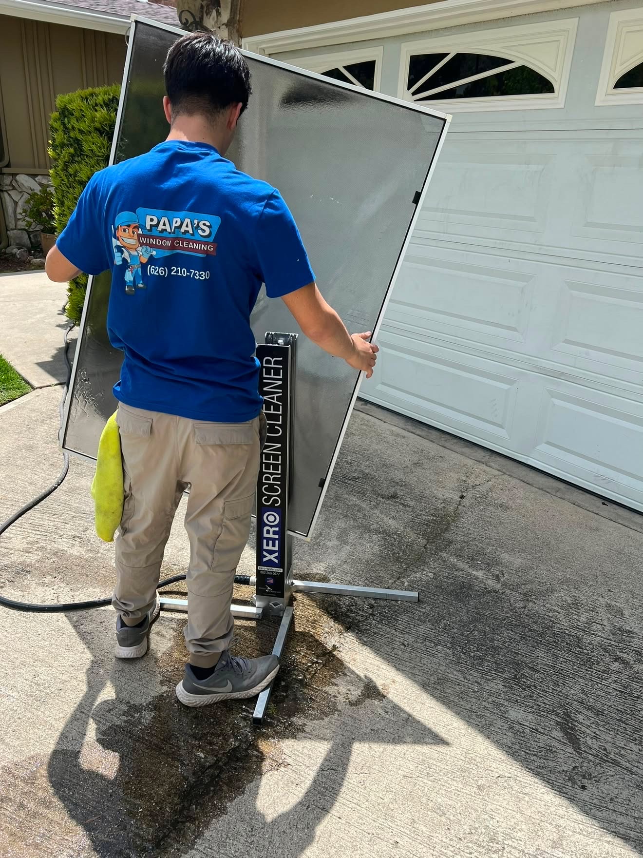 Papa's technician deep cleaning a window screen on a Xero screen stand