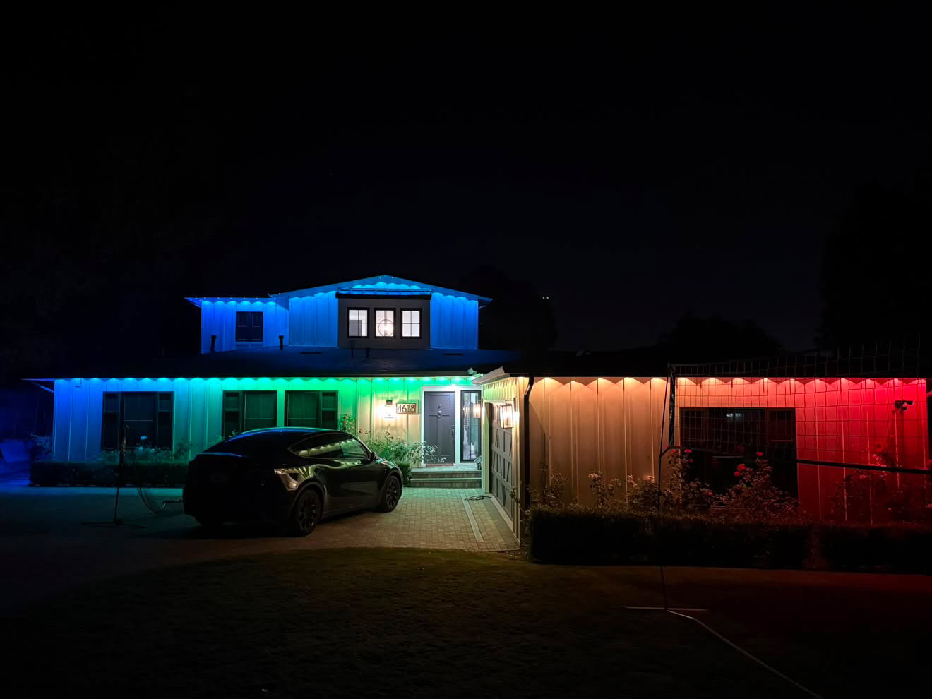 Color-changing permanent roofline lighting across a two-story home at night