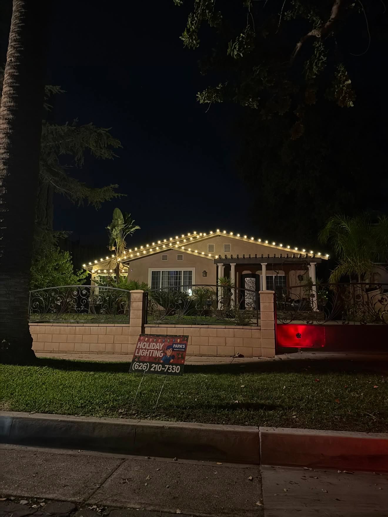 Warm white roofline lighting with Papa's yard sign