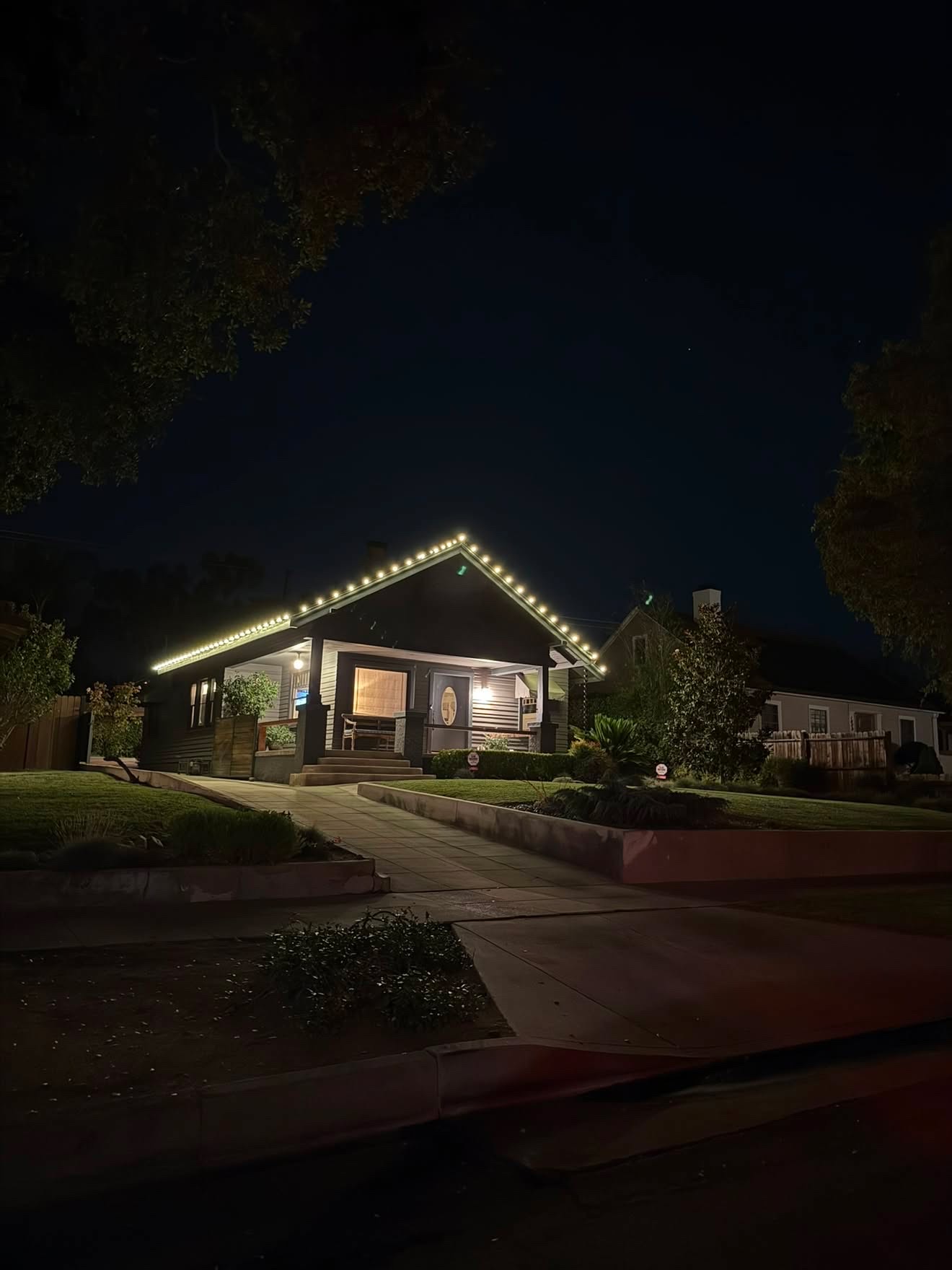 Craftsman bungalow with warm white roofline Christmas lights at night
