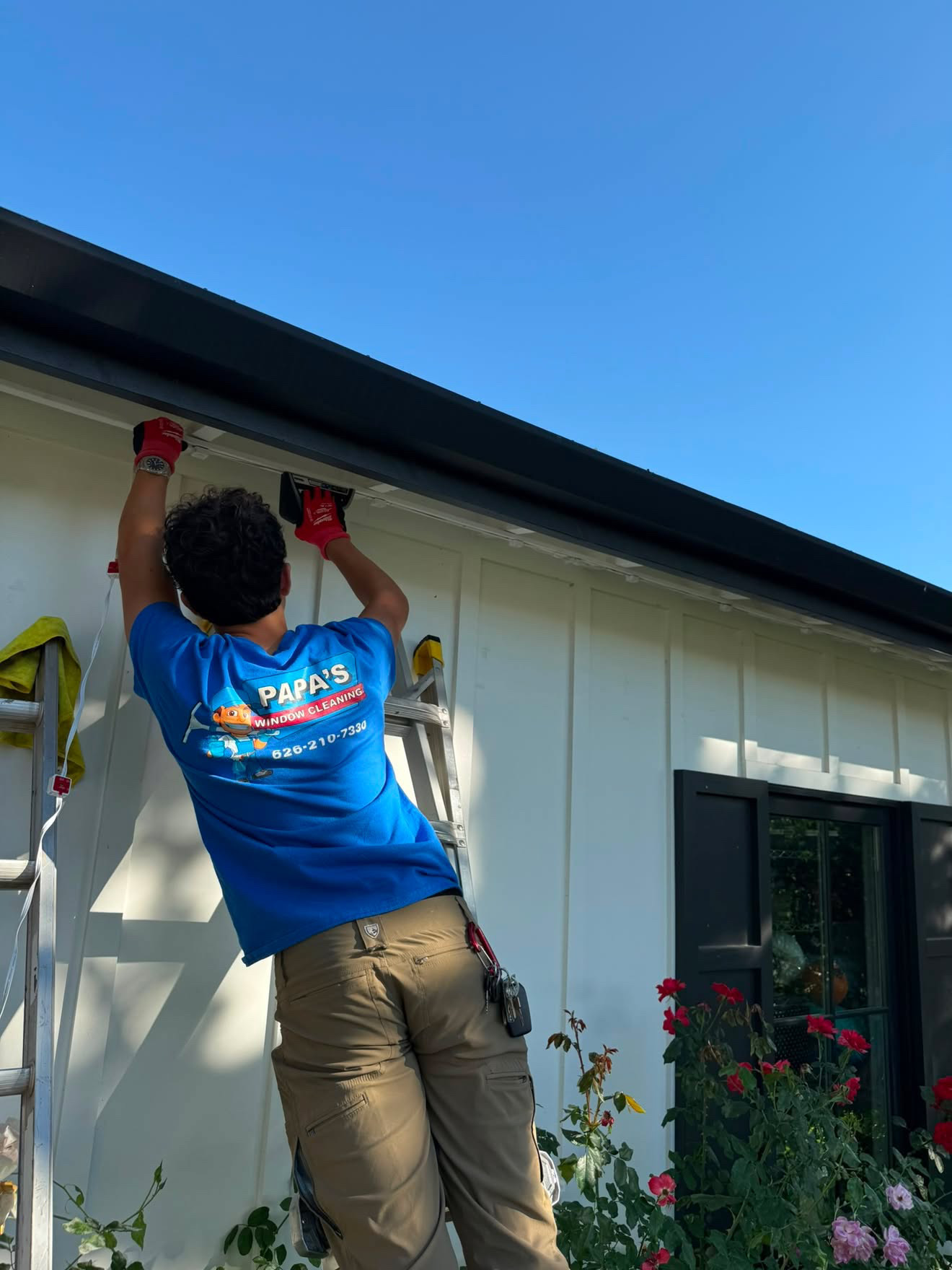 Papa's technician installing roofline Christmas light clips on a ladder